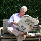 Jubilado leyendo  tranquilamente el diario en un banco