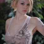Bella rubia posando eróticamente  sobre el sofá mientras se desnuda
