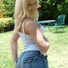 Sonriente rubia posando desnuda en el jardín para nosotros